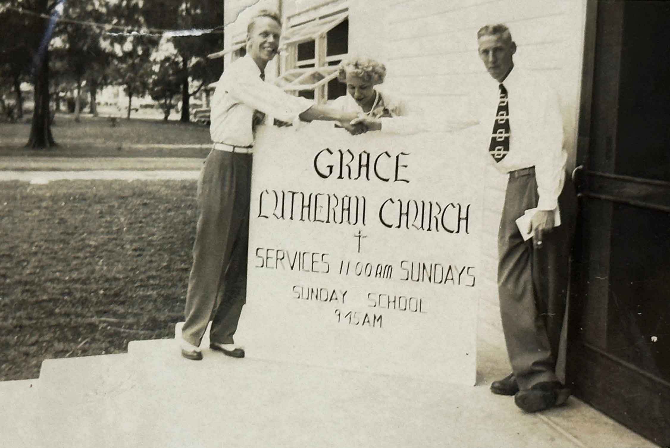 George Elbrecht, Ora Lee Carr and Pastor Albert Schmidt stand beside a sign announcing Lutheran services at the Miami Springs Recreation Center (now the site of the MS Library) in February of 1949. (Courtesy Grace Lutheran Church)